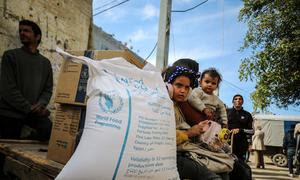 Una familia palestina recibe la ayuda alimentaria de la ONU en un centro de distribución de Nusierat, Gaza.