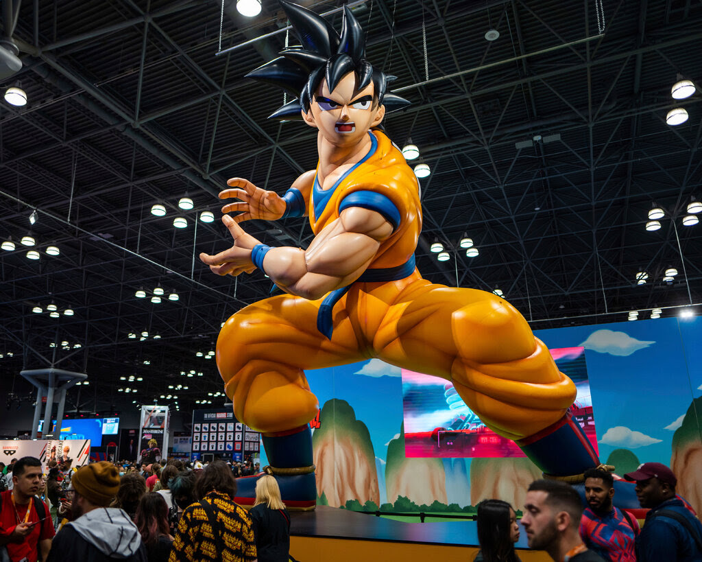 A large statue of an anime character in an orange outfit with blue trim. He has spikey black hair and is positioned in a crouch with his arms twisted to one side.