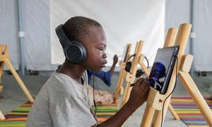 Unos niños participan en una sesión de aprendizaje electrónico en el centro de reunión de desplazados internos de Al Seniyaa, en Port Sudan.