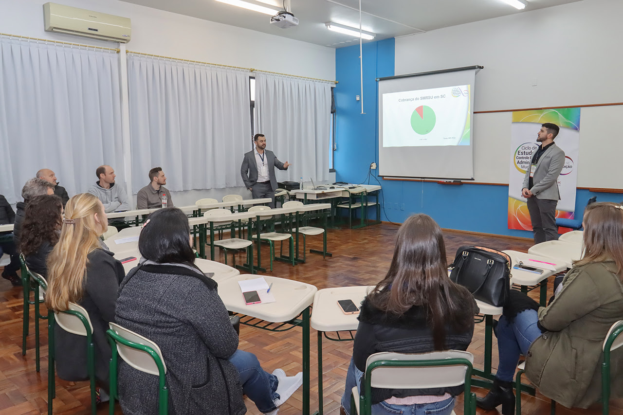 Foto de dois servidores do TCE/SC apresentando palestra em uma sala de aula. 