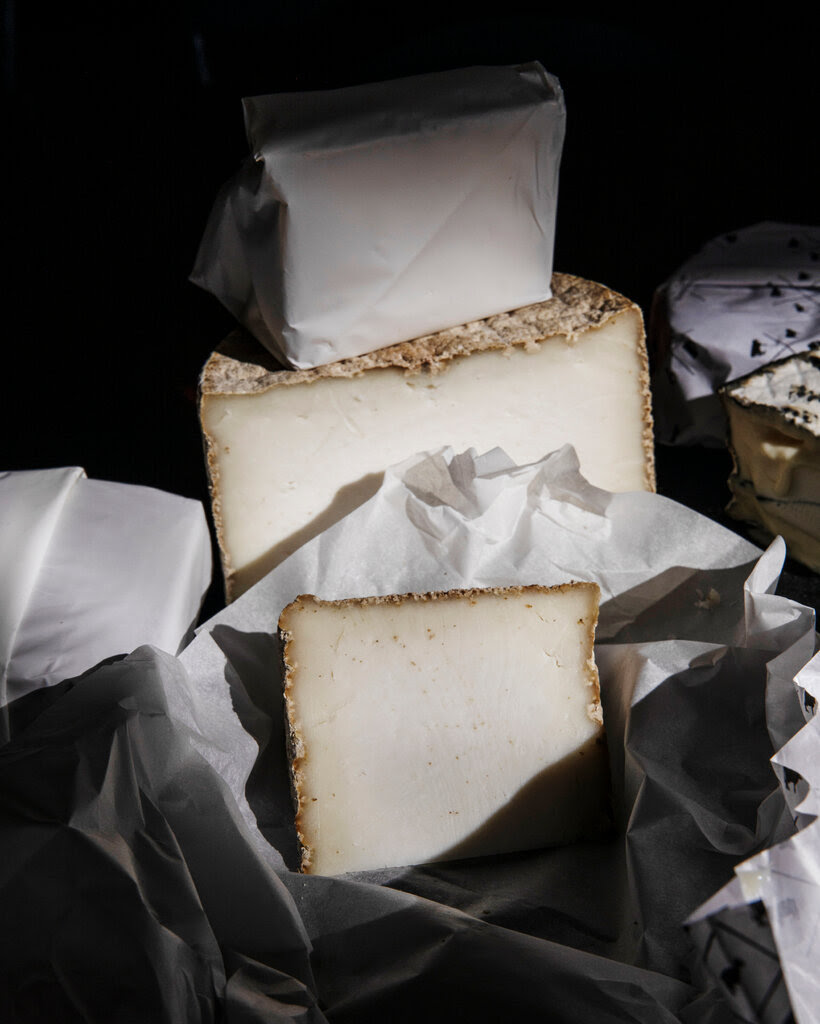 Three wedges of cheese are photographed in moody lighting.