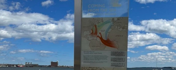 a view of the middle passage marker on long wharf, with the harbor and a blue sky behind