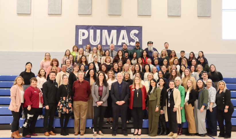 Governor Jared Polis with all the GVA staff standing in front of the PUMAS banner in the new gym