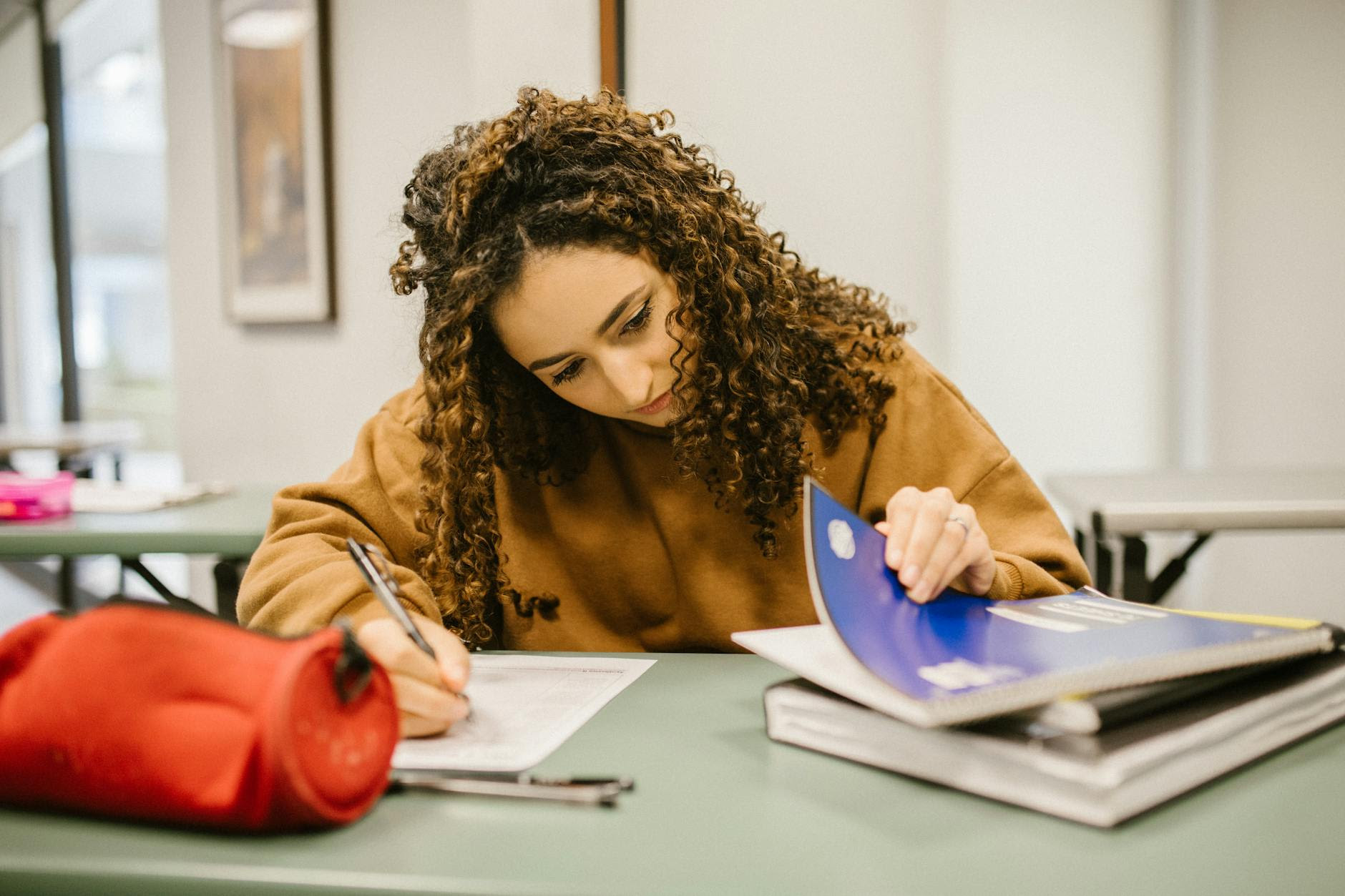 A college student studying diligently at a desk with textbooks and notes.