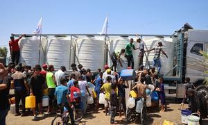 Niños y sus familias recogen agua de un depósito de agua apoyado por UNICEF en Deir Al-Balah, en la Franja de Gaza.