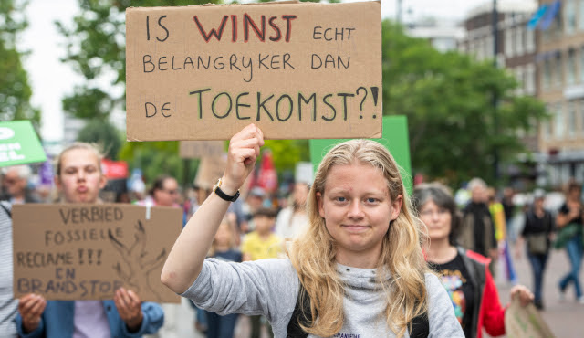 Een jonge deelnemer aan de Klimaatmars in Rotterdam in juni 2022 houdt een zelfgemaakt protestbord omhoog met daarop de tekst ‘Is winst echt belangrijker dan de toekomst?!’