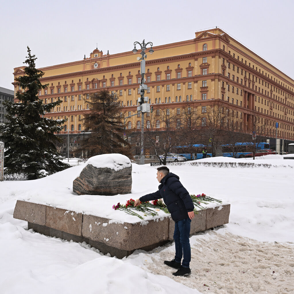 A man dressed in a black winter jacket lays flowers at a monument to the victims of political repression in Moscow. 