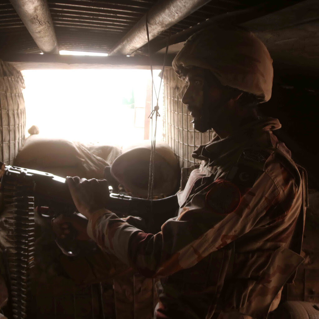 A person in a helmet holds a long gun in a bunkerlike space.