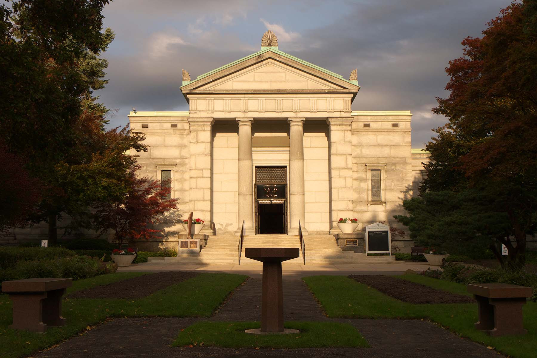 A photo of the mausoleum and chapel at Mt. Pleasant Cemetery in Toronto, cast in a ray of light with dark clouds behind it