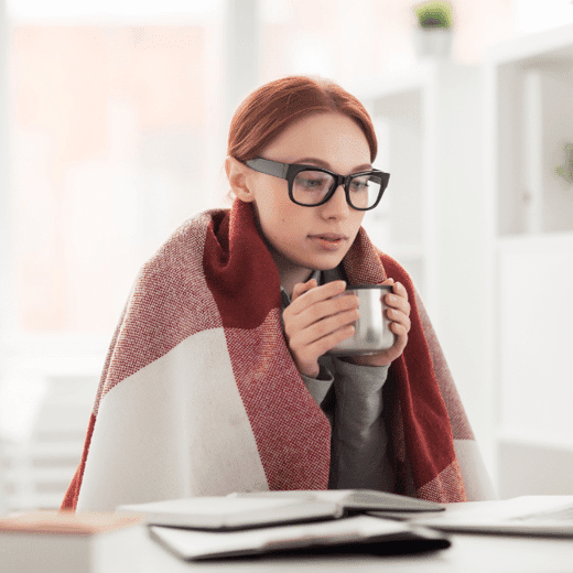 Woman holding mug while wearing a blanket