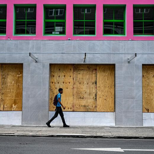 A man walks past boarded up shop windows before the arrival of Hurricane Beryl in Bridgetown, Barbados on June 30, 2024. Beryl, the first hurricane of the 2024 Atlantic season, strengthened into an "extremely dangerous" Category 4 storm Sunday as it threatened the southeast Caribbean with potentially life-threatening winds and storm surge, US trackers said. (Photo by CHANDAN KHANNA / AFP)