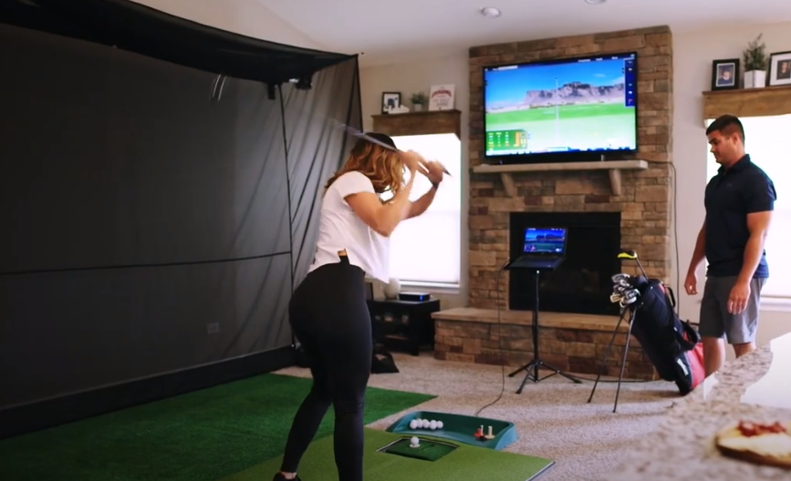 A person playing golf in a room
Description automatically generated