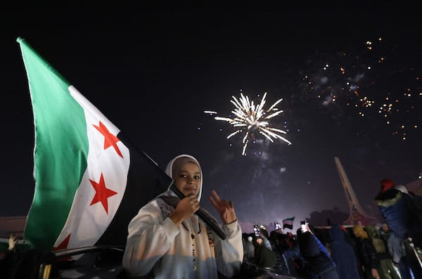 A young woman holds the Syrian flag on New Year's Day in Damascus. AFP