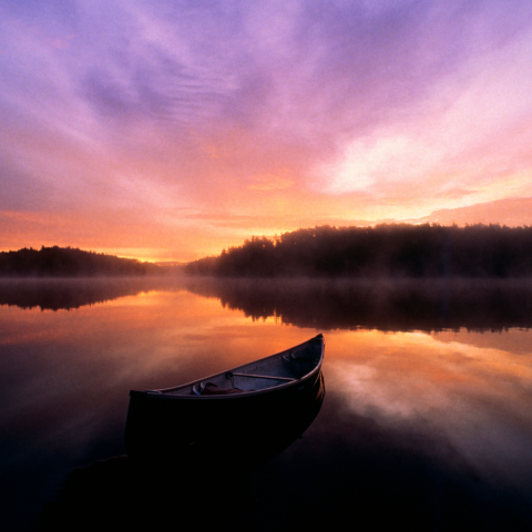Sunset over a lake with a empty canoe on the water