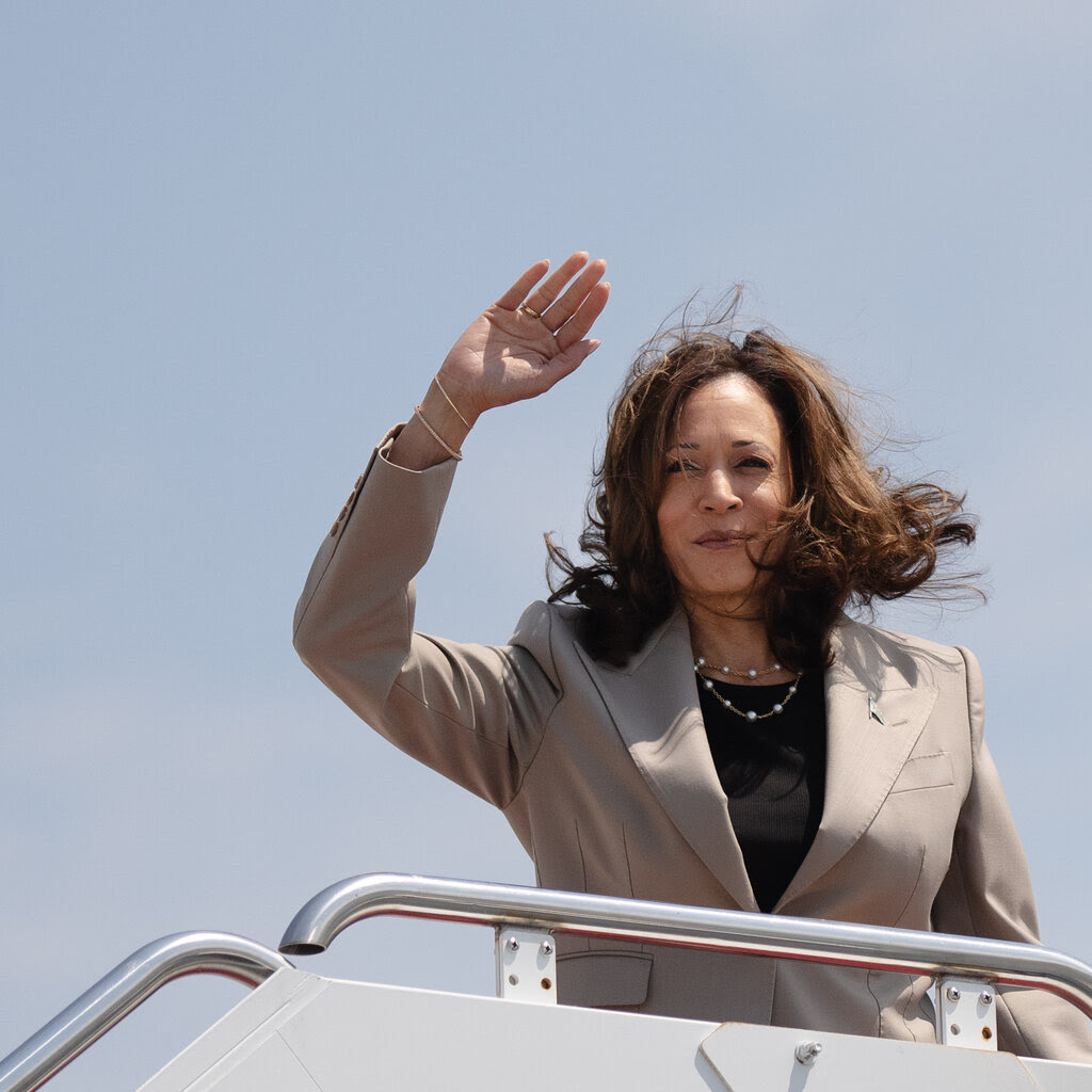 Vice President Kamala Harris waves her hand as her hair blows in the wind.