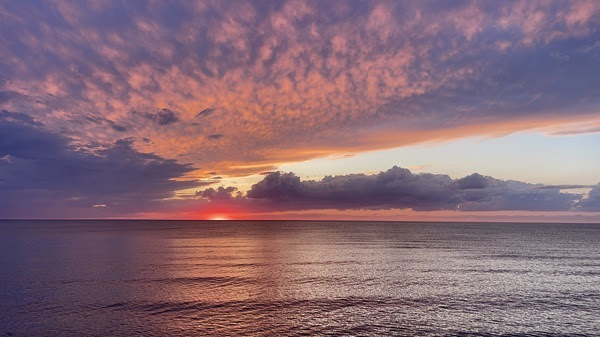 calm, rippled water stretches out on Lake Superior under a brilliant pink and purple sunset at McLain State Park in Houghton County