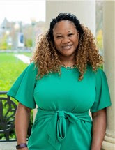 A photo of Yolanda Avent. She is outside wearing a green dress and smiling.