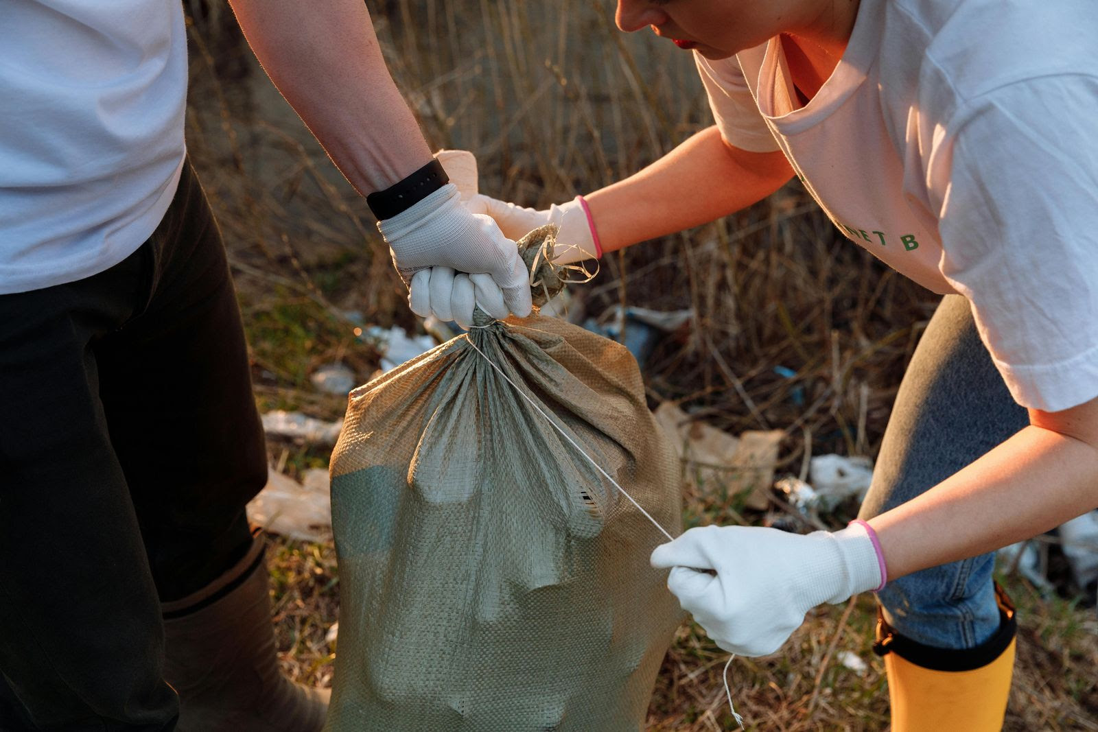 dos personas sosteniendo una bolsa de basura con guantes