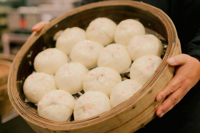  A circular wooden tray containing freshly made dumplings at New Town Bakery, held in the hands of Robert Sung