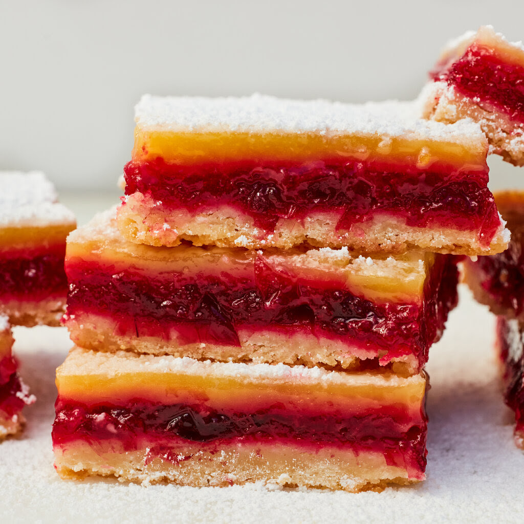 A pile of three slices of cake bars made of layers of cranberry, lemon and pastry.