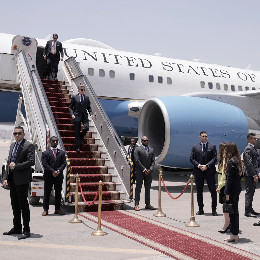 U.S. Secretary of State Antony Blinken walks down the boarding stairs of an airplane.