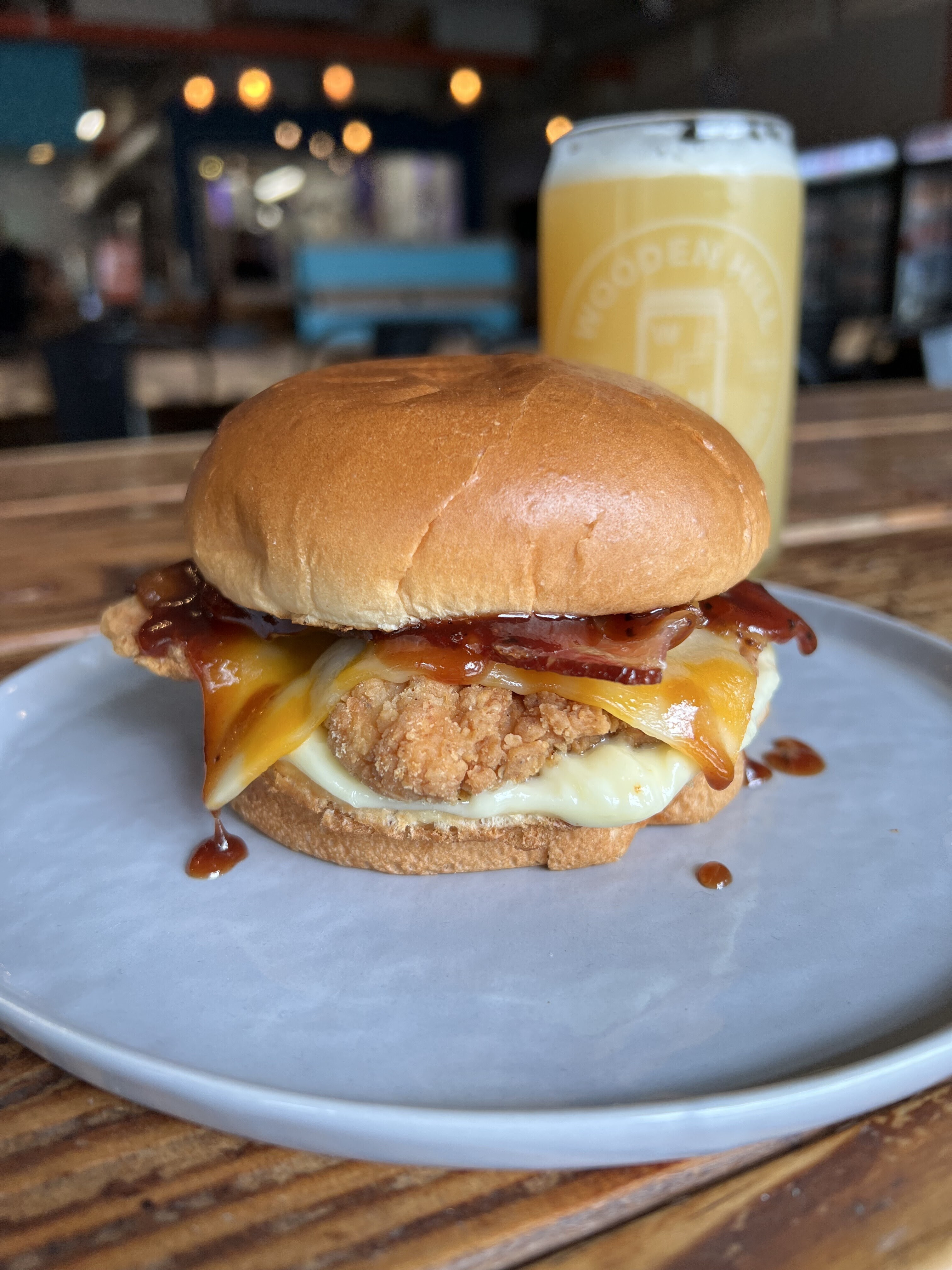 BBQ Bacon Chicken Sandwich on a Plate. Beer in the Background.