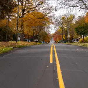 A road with new pavement on a fall afternoon.
