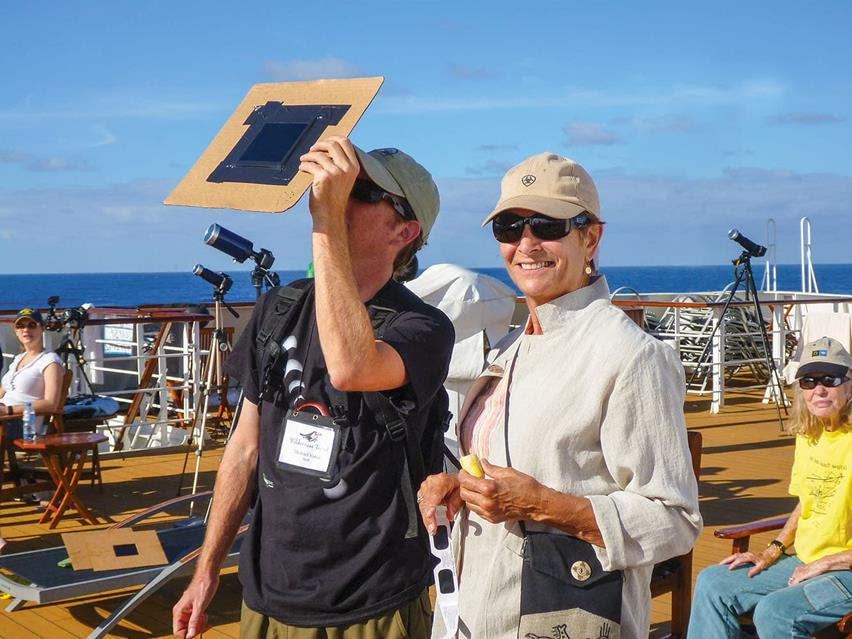 Two Wilderness Travel guests test a homemade eclipse viewing device on deck.