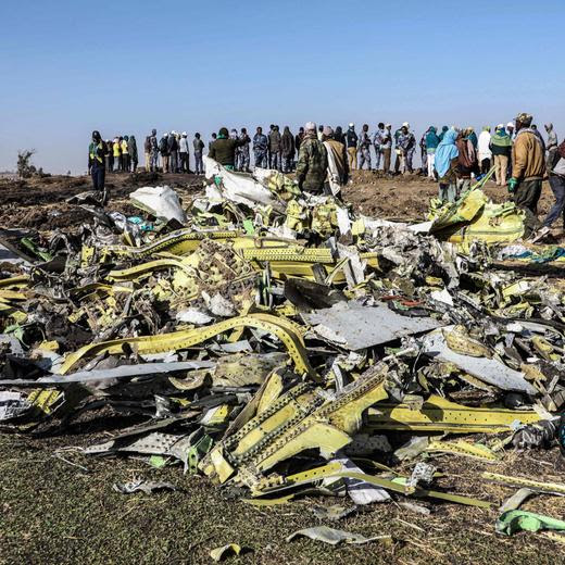 (FILES) People stand near collected debris at the crash site of Ethiopia Airlines near Bishoftu, a town some 60 kilometres southeast of Addis Ababa, Ethiopia, on March 11, 2019. Boeing reached a last-minute settlement November 11, 2024, to avert a civil trial in connection with the Ethiopian Airlines crash of a 737 MAX plane that killed 157 people. With a trial due to begin November 12, several sources close to the case told AFP the company and the family of a young woman killed in the 2019 tragedy reached a settlement, which must still be approved by a judge. (Photo by Michael TEWELDE / AFP)