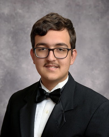 a senior style photo of Edres Saleem, he is wearing a black tuxedo jacket, black bowtie and white shirt