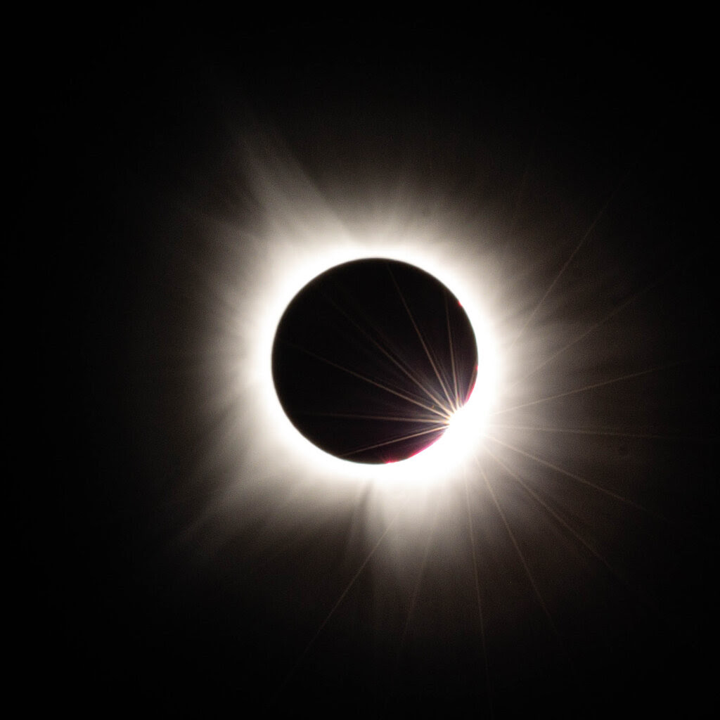 A black background with a black circle in the center. There is a white ring around it (which is the sun).