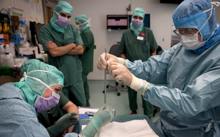 Two of the clinical team prepare the needle in the operating room.