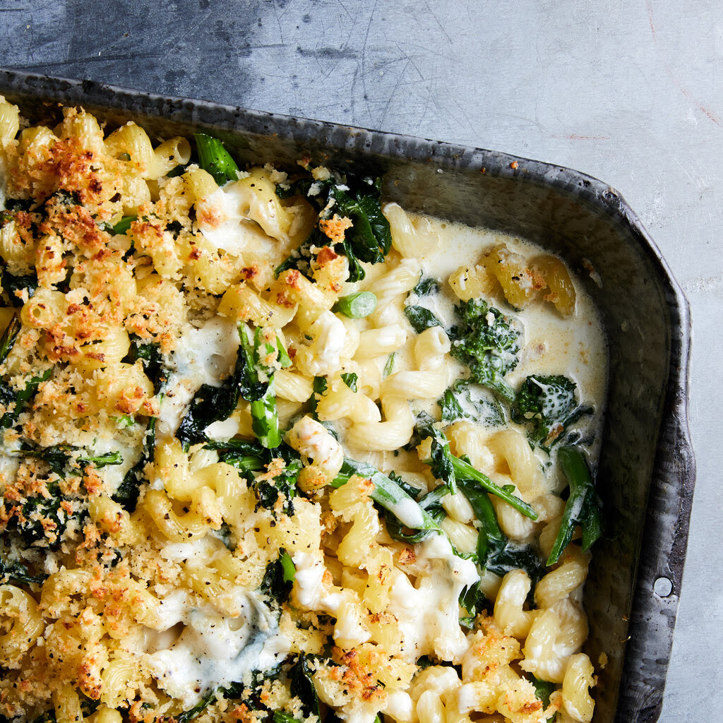 Macaroni noodles in a cream sauce with broccoli rabe and breadcrumbs in a baking dish.