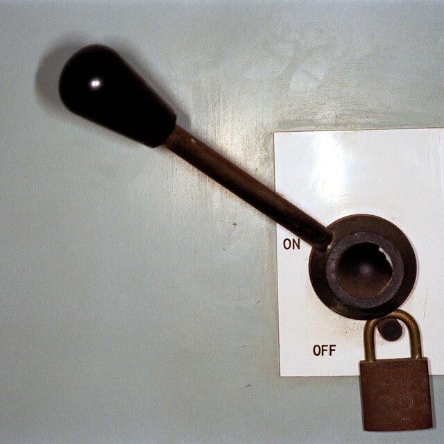 A lever against a gray wall, pointing toward “on” and away from “off.” 