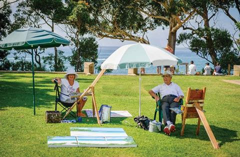 A man and a woman sit and paint in Huskisson