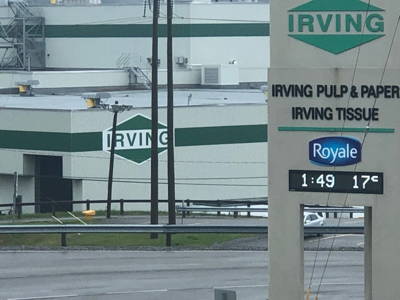 A photo of a grewt buildinbg with dark green strikes and the Irving logo on it.There is a lso a sign with a digital clock and current temperative dispayed.