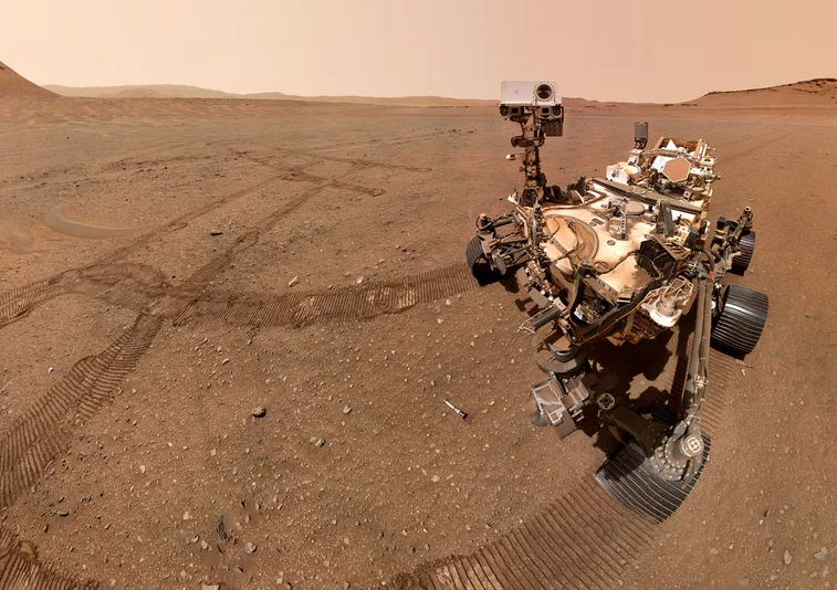 A selfie of NASA's Perseverance Mars rover with sample tubes it deposited at a sample depot it is creating within an area of Jezero Crater nicknamed "Three Forks." The ninth tube dropped during the construction of the depot, containing the sample the science team refers to as "Atsah, " can be seen in front of the rover. Other sample tubes are visible in the background.