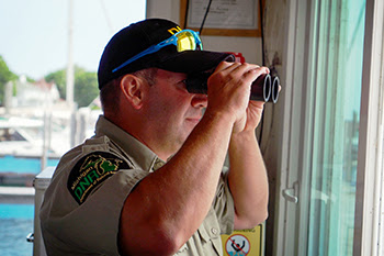 A harbormaster looks through a pair of binoculars.