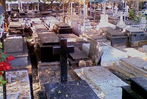 A cemetery shows graves arranged closely together.