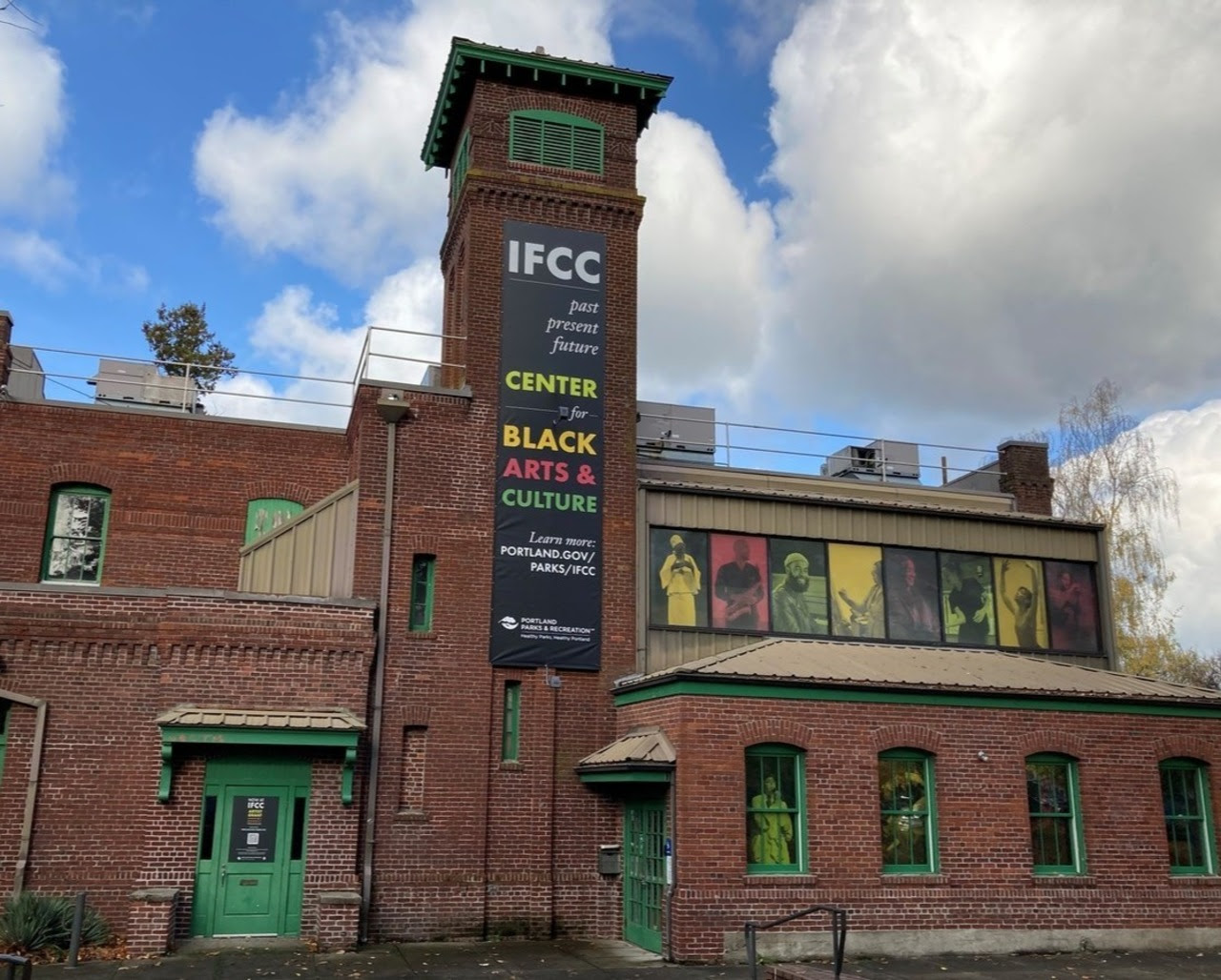 IFCC, a former brick firehouse with green trim and colorful banners showcasing local Black artists. The main banner says IFCC past present future Center for Black Arts & Culture
