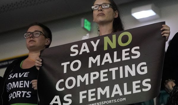 Protesters hold signs as University of Pennsylvania transgender athlete Lia Thomas competes in the 200 freestyle finals at the NCAA Swimming and Diving Championships Friday, March 18, 2022, at Georgia Tech in Atlanta. Thomas finished tied for fifth place. (AP Photo/John Bazemore) **FILE**