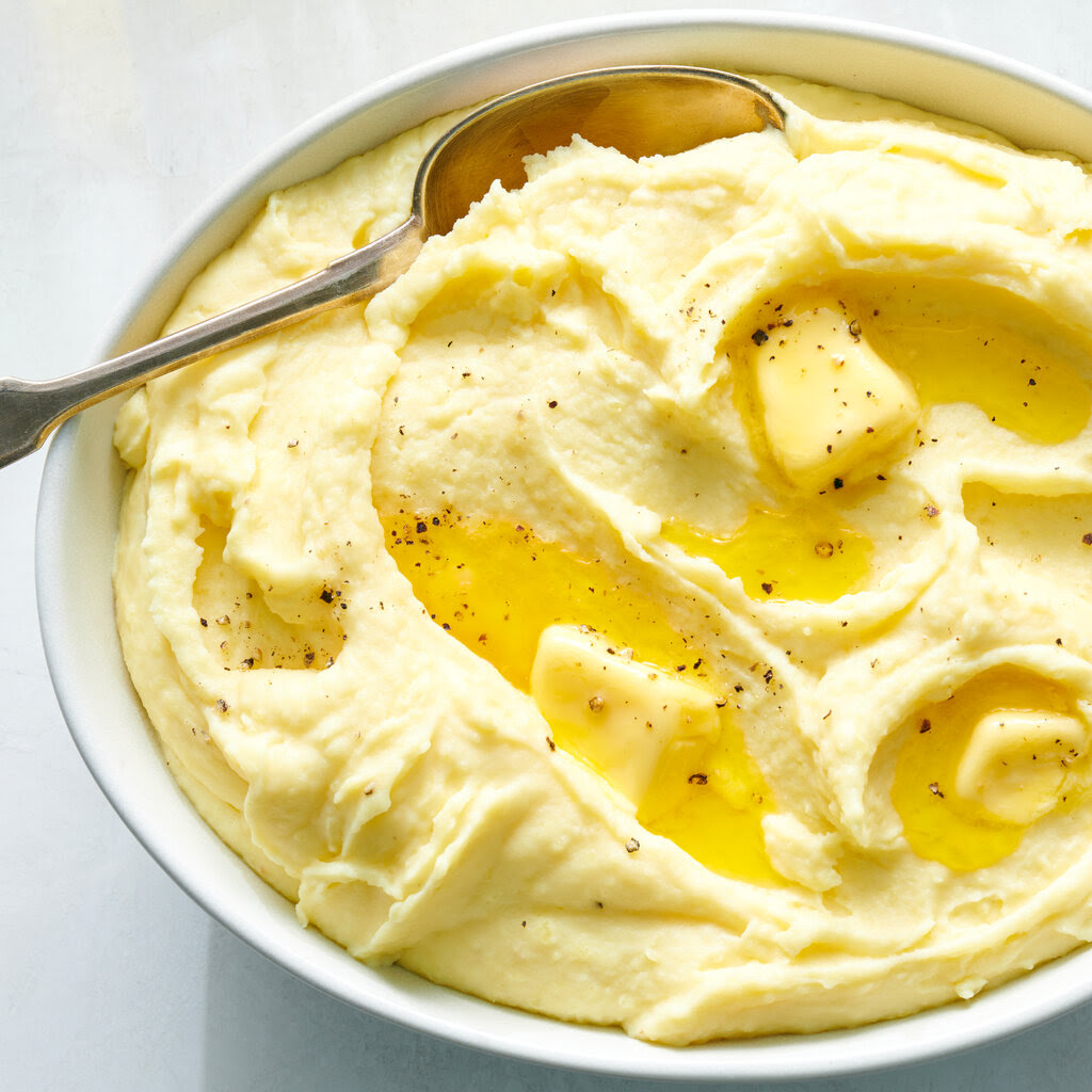 Butter melting into a dish of mashed potato, with a few flecks of pepper on top of it.