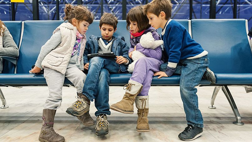 Niños esperan un vuelo en el aeropuerto de Lisboa jugando