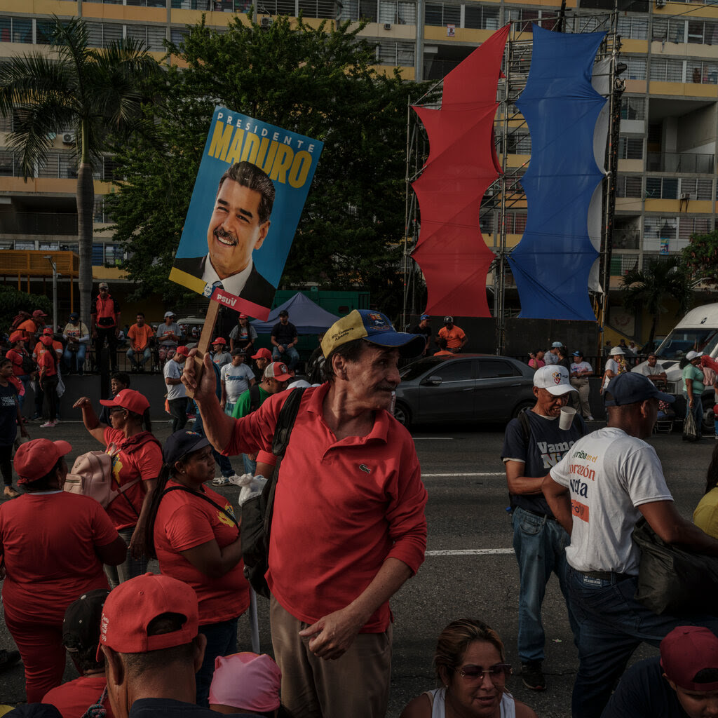 People in the streets with on person holding a campaign poster with an image of President Nicolás Maduro.