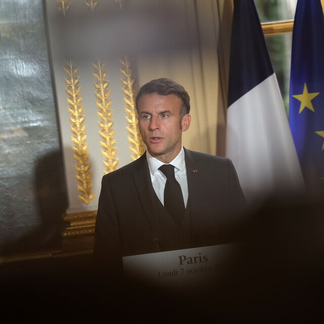 A man in a suit behind a lectern. 