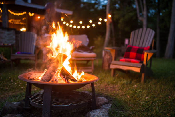 Empty chairs by a roaring bonfire in a firepit container