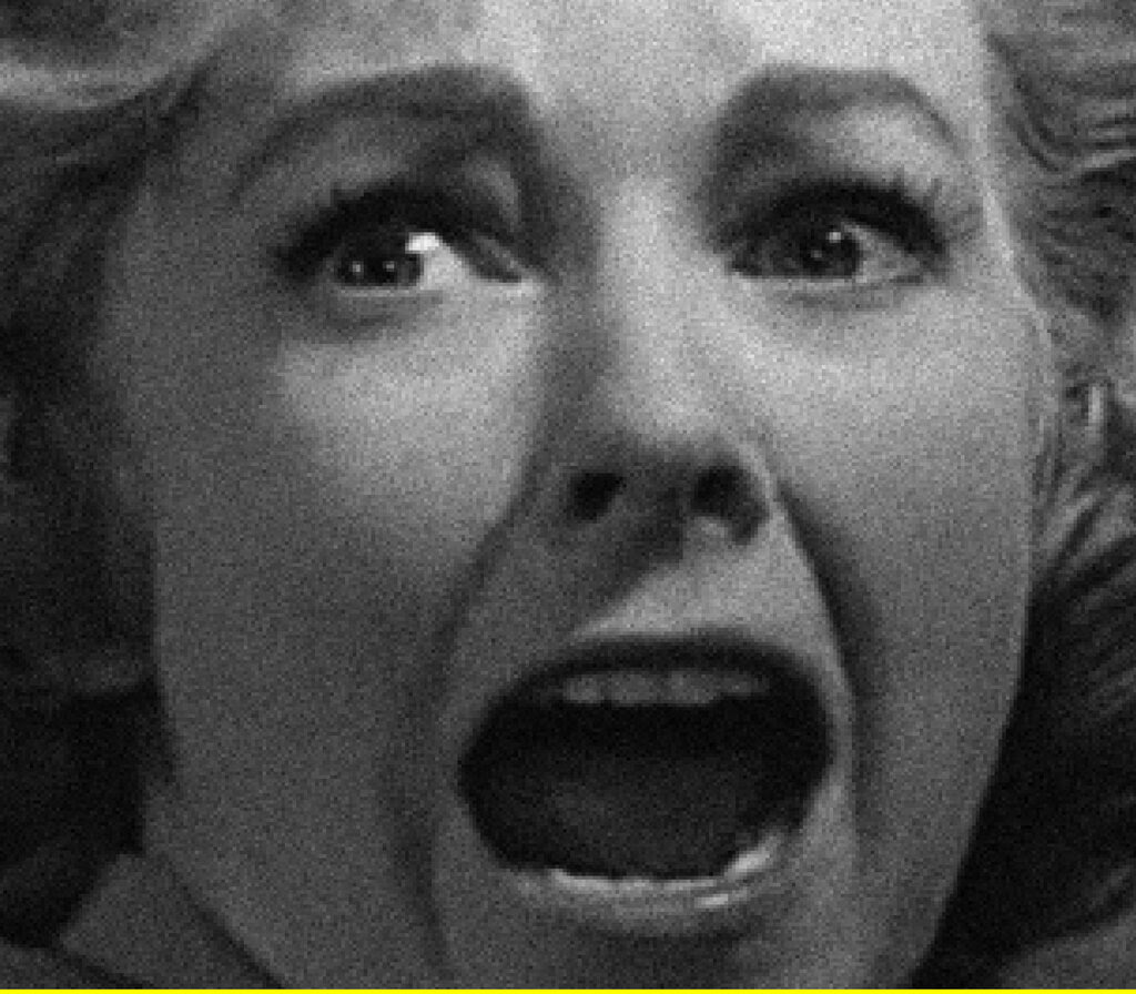 A close-up still from a black-and-white film shows a woman screaming.