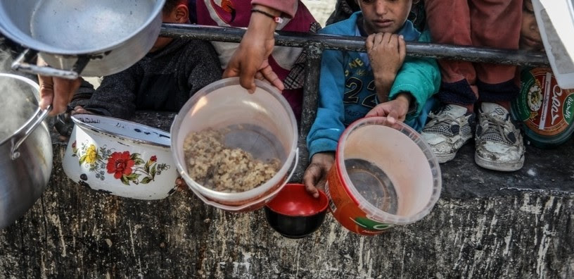 Des enfants affamés à Gaza tendent des récipients en attendant de la nourriture.