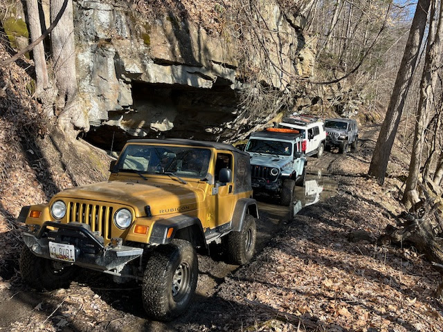 Four vehicles traverse an off-highway trail at Wolf Den Run State Park.