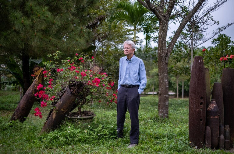Chuck Searcy, 79, co-founder of a group that works to deactivate unexploded bombs in Vietnam, a legacy of the war. He stood next to deactivated ordnance in Dong Ha City, Quang Tri Province, last month.